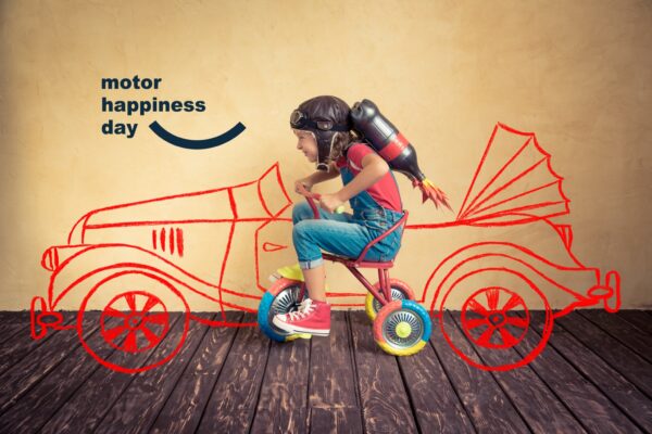 Motor Happiness Day – immagine coordinata dell’evento Motor Happiness Day: bambina con casco e razzo su un triciclo davanti a un’auto disegnata